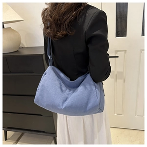 Lifestyle shot of light blue nylon crossbody bag featuring an adjustable strap and crescent shape