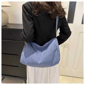 Blue nylon crossbody crescent bag shown on model with shoulder strap detail