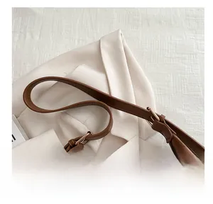 Detail eines karamellbraunen Lederriemens mit goldener Metallschnalle an Retro-Tasche