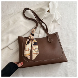 Detail of dark brown tote bag with contrast stitching and decorative scarf accessory