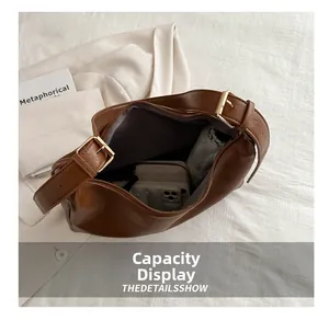 Innenkapazität der braunen PU-Ledertasche mit Alltagsgegenständen und goldenen Beschlägen