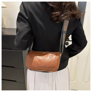 Close-up of retro brown crossbody bag with bohemian printed strap on female model