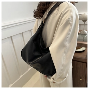 Detail of black leather hobo bag featuring adjustable shoulder strap with gold metal buckle