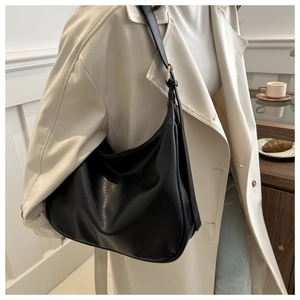 Detail der schwarzen Hobo-Tasche aus genarbtem Leder mit verstellbarem Riemen und Goldakzenten
