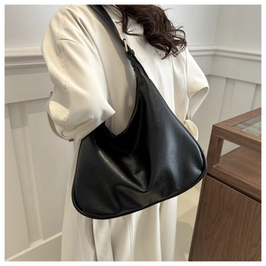 Detail einer schwarzen Hobo-Tasche aus Kieselleder, getragen von einem Modell in einem Raum