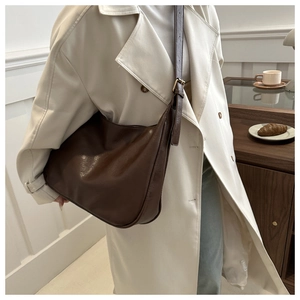 Detail der dunkelbraunen Leder-Einkaufstasche mit verstellbarem Riemen am Outfit