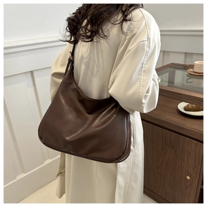 Detail of dark brown leather crossbody bag with vintage wax texture and moon shape