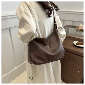 Seitenansicht der dunkelbraunen Hobo-Tasche aus Leder, von einem Model getragen
