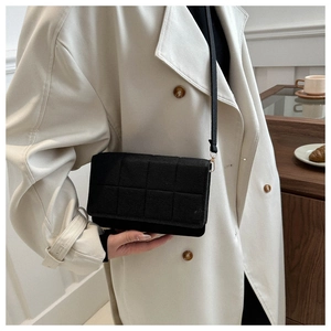 Detalle de bolso bandolera acolchado negro con herrajes dorados y textura de gamuza elegante