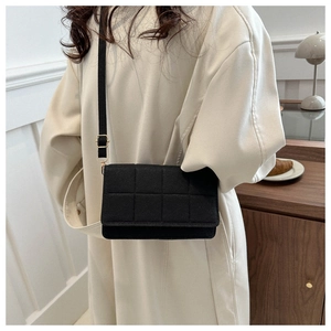 Detalle de bolso bandolera acolchado negro con correa ajustable en ambiente hogareño