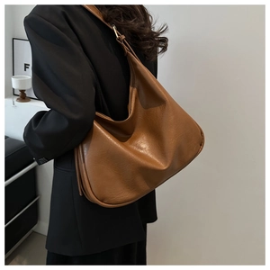 Rear view of model wearing a vintage brown hobo bag with adjustable metal buckle strap