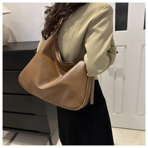 Braune Hobo-Schultertasche mit breitem Gurt, getragen von Model im Innenraum