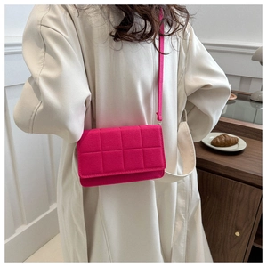 Detalle de un bolso bandolera acolchado de fieltro magenta llevado por una modelo