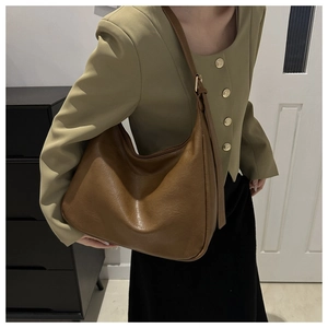 Side view of brown faux leather half-moon bag showing adjustable strap and large capacity