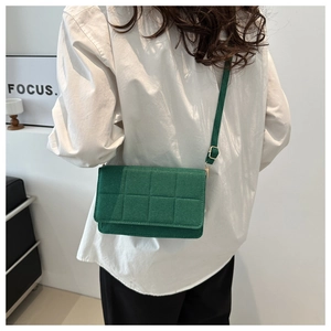 Bolso bandolera acolchado verde con detalles dorados en el hombro de la modelo