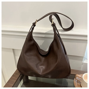 Detail of a dark brown Hobo shoulder bag with gold hardware on a wooden table