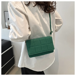 Detalle de bolso bandolera verde oscuro con costuras geométricas llevado por una modelo