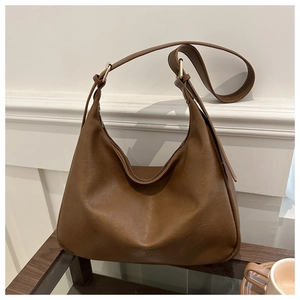 Detail of a brown half-moon tote bag with premium leather texture and gold hardware details