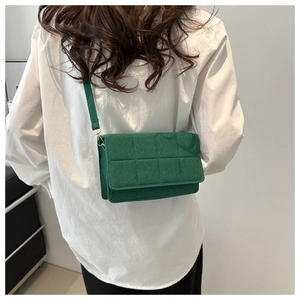 Modelo con bolso bandolera de fieltro verde oscuro con diseño acolchado cuadrado y solapa