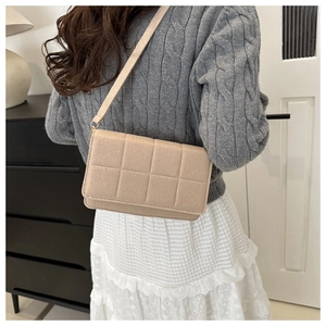 Primer plano de bolso bandolera beige acolchado con costuras suaves en modelo