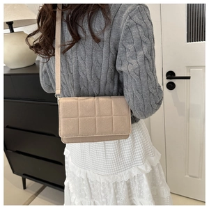 Primer plano del bolso bandolera de fieltro acolchado beige con elegante diseño de solapa