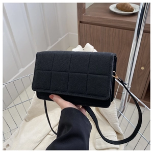 Detalle de bolso bandolera de fieltro acolchado negro con elegantes herrajes dorados mate