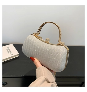 Détail d'un sac de soirée à paillettes argentées avec fermoir cristal et poignée dorée