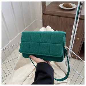 Detalle de bandolera de fieltro verde con patrón acolchado y correa delgada de hombro