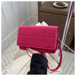 Primer plano del bolso bandolera de fieltro rosa fucsia con costuras acolchadas