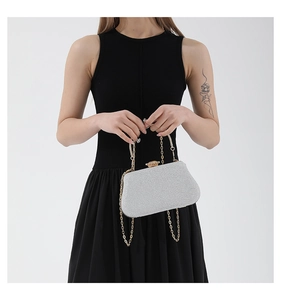 Close-up of silver glitter evening bag with sparkling rhinestone clasp and gold metal chain