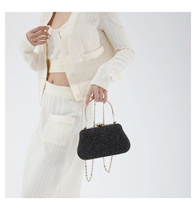 Detail of black glitter evening clutch with round gold metal handle and chain strap