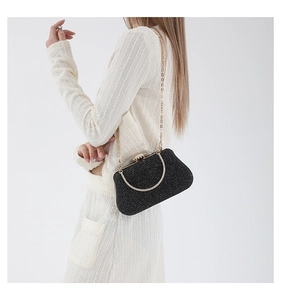 Detail of black glitter evening bag with gold metal frame and delicate chain strap