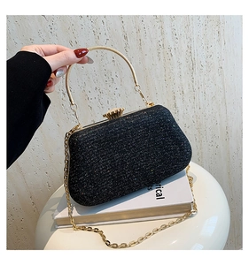 Close-up of black glitter evening bag with gold metal handle and floral jewel clasp