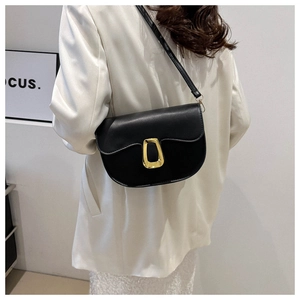 Detail of black leather saddle bag with gold geometric buckle and shoulder strap