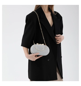 Detail of silver sequined evening clutch with gold bow clasp and elegant chain strap