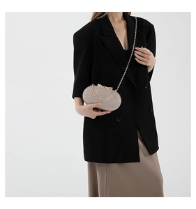 Detail of champagne gold sequin evening clutch with golden bow clasp and chain strap