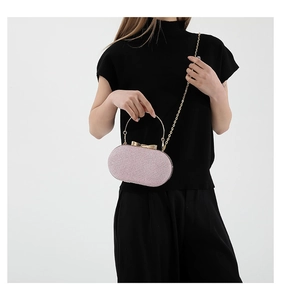 Pink sequin evening clutch bag with golden bow clasp and chain strap held by model