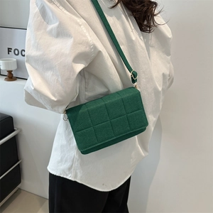 Bolso bandolera verde minimalista con diseño acolchado mostrado por modelo en estudio