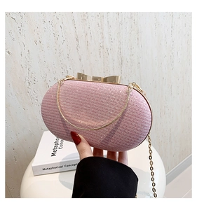 Detail of pink sequin clutch bag featuring golden bow clasp and delicate chain strap