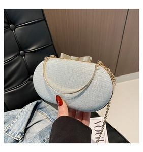 Silver glitter evening clutch bag with gold bow clasp and chain in lifestyle setting