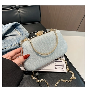 Detail view of light blue sequined evening clutch bag with gold chain on a leather seat