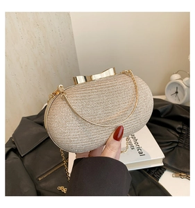 Close-up of champagne gold oval evening clutch with bow clasp and metal chain