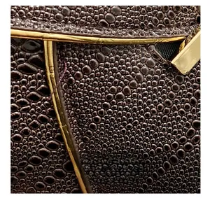 Detailed macro view of dark brown pebbled grain leather texture and gold metal trim