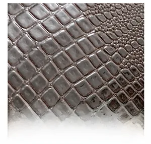 Detailed macro view of dark brown faux crocodile leather texture on handbag surface