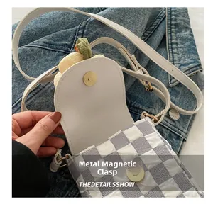 Close-up of checkered crossbody phone bag with gold magnetic snap button closure