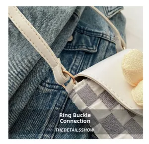 Macro shot of stylish checkered bag showing gold ring buckle and white leather strap