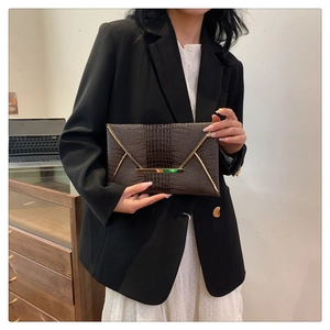 Dettaglio della pochette marrone scuro goffrata coccodrillo con fibbia metallica a V oro