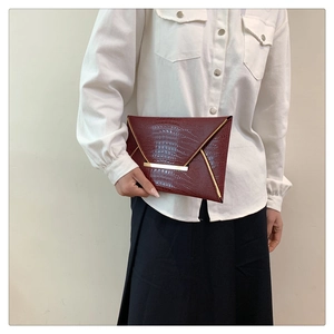 Dettaglio della pochette bordeaux a busta effetto coccodrillo con bordo oro