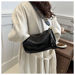 Détail du sac croissant en cuir noir avec large bandoulière ethnique et bijou de sac