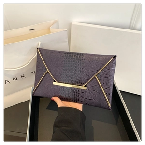 Dettaglio della pochette a busta viola scuro con trama a coccodrillo e finiture dorate
